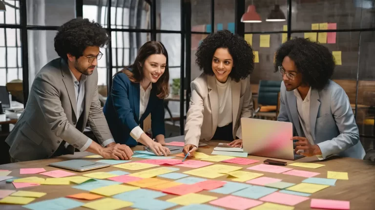 Pessoas analisando notas adesivas coloridas em uma mesa de escritório moderno com janelas grandes.